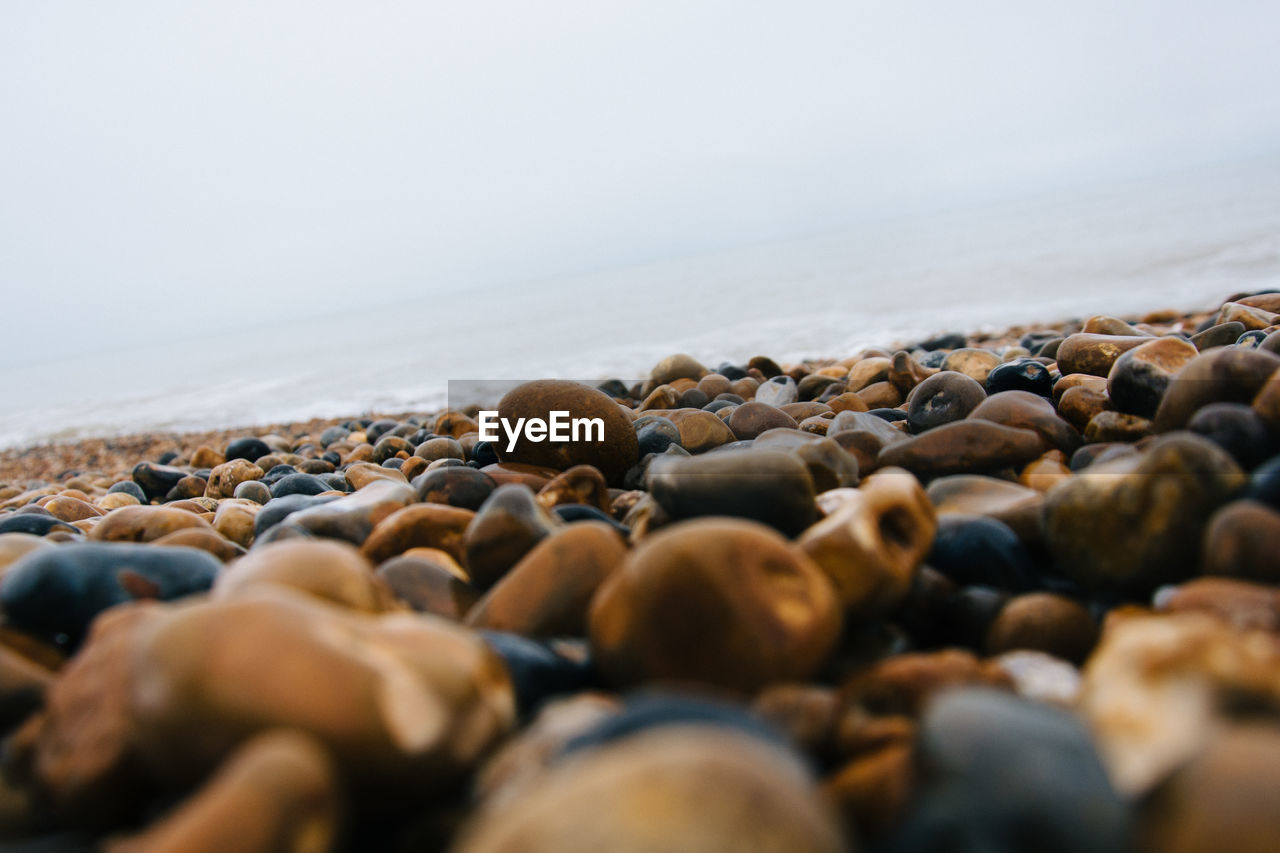 Surface level of pebble beach against clear sky