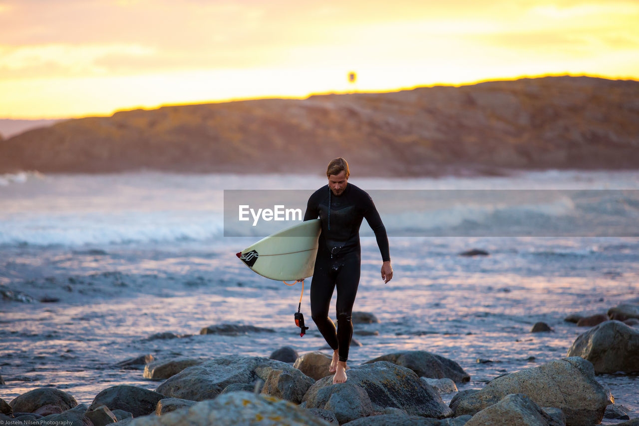 FULL LENGTH OF MAN STANDING ON ROCK AT BEACH