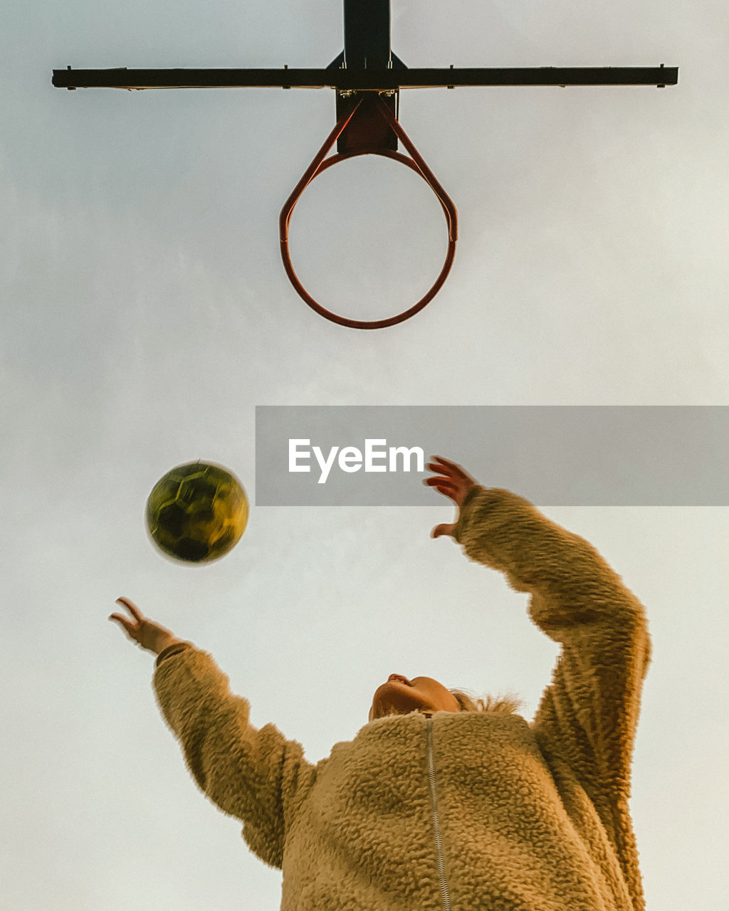 Low angle view of woman playing basketball against sky