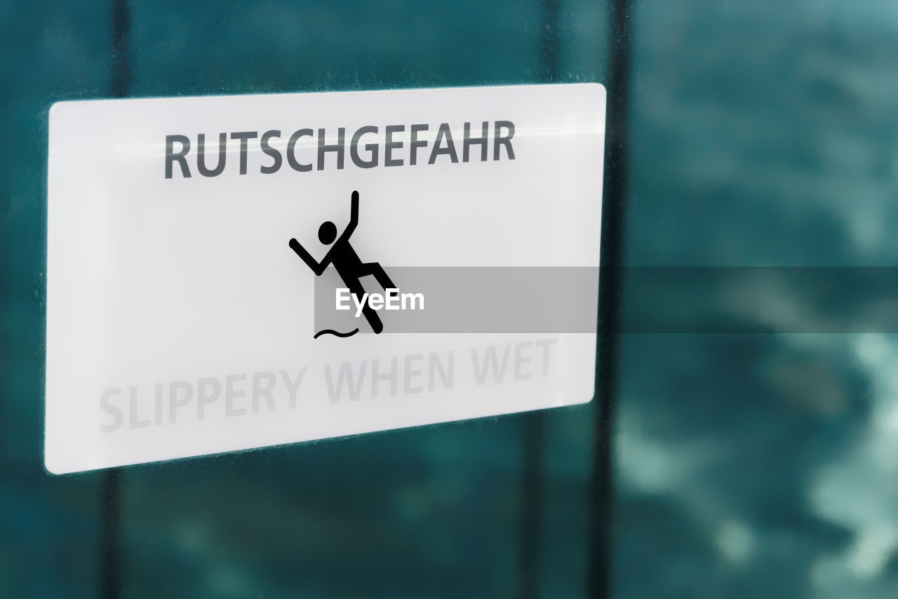 Close-up of warning sign slippery when wet in german and english