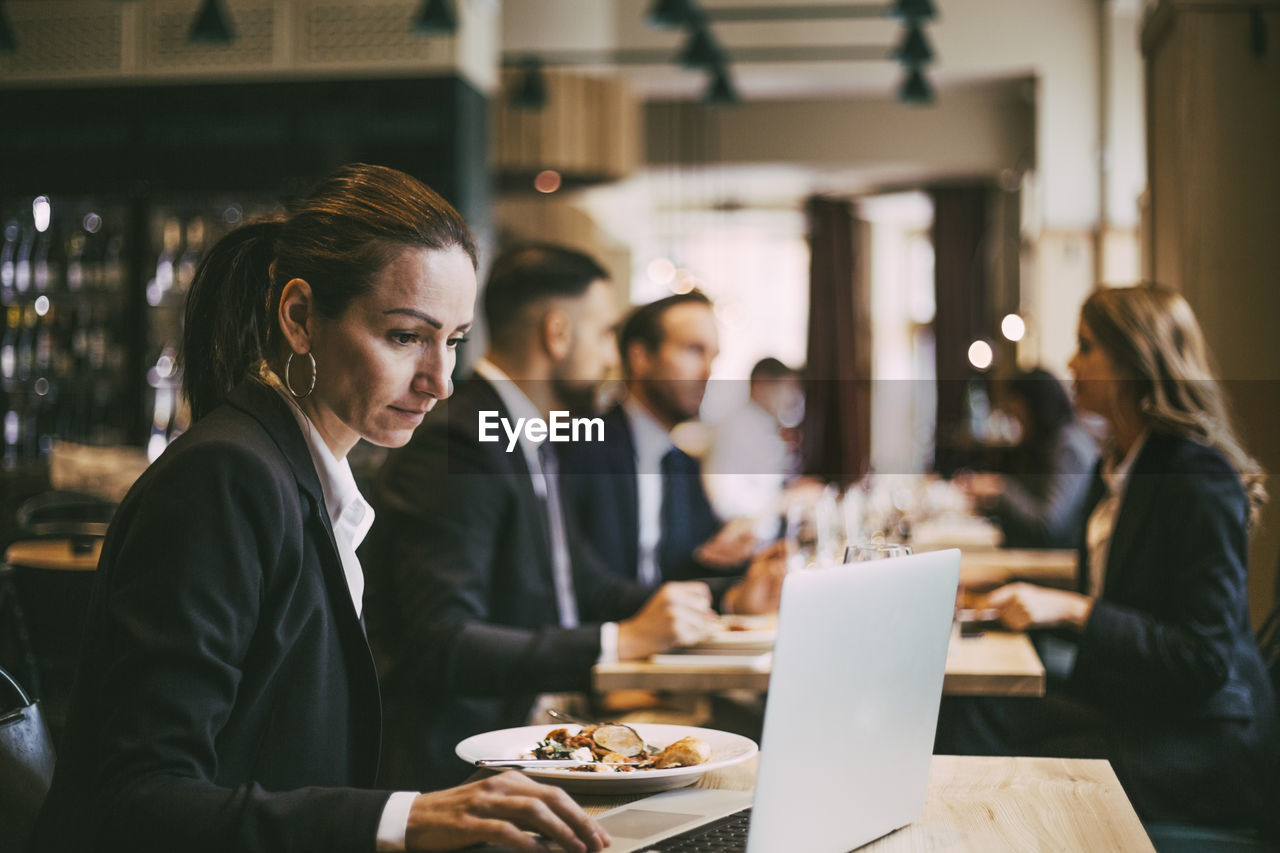 Side view of businesswoman using laptop in restaurant