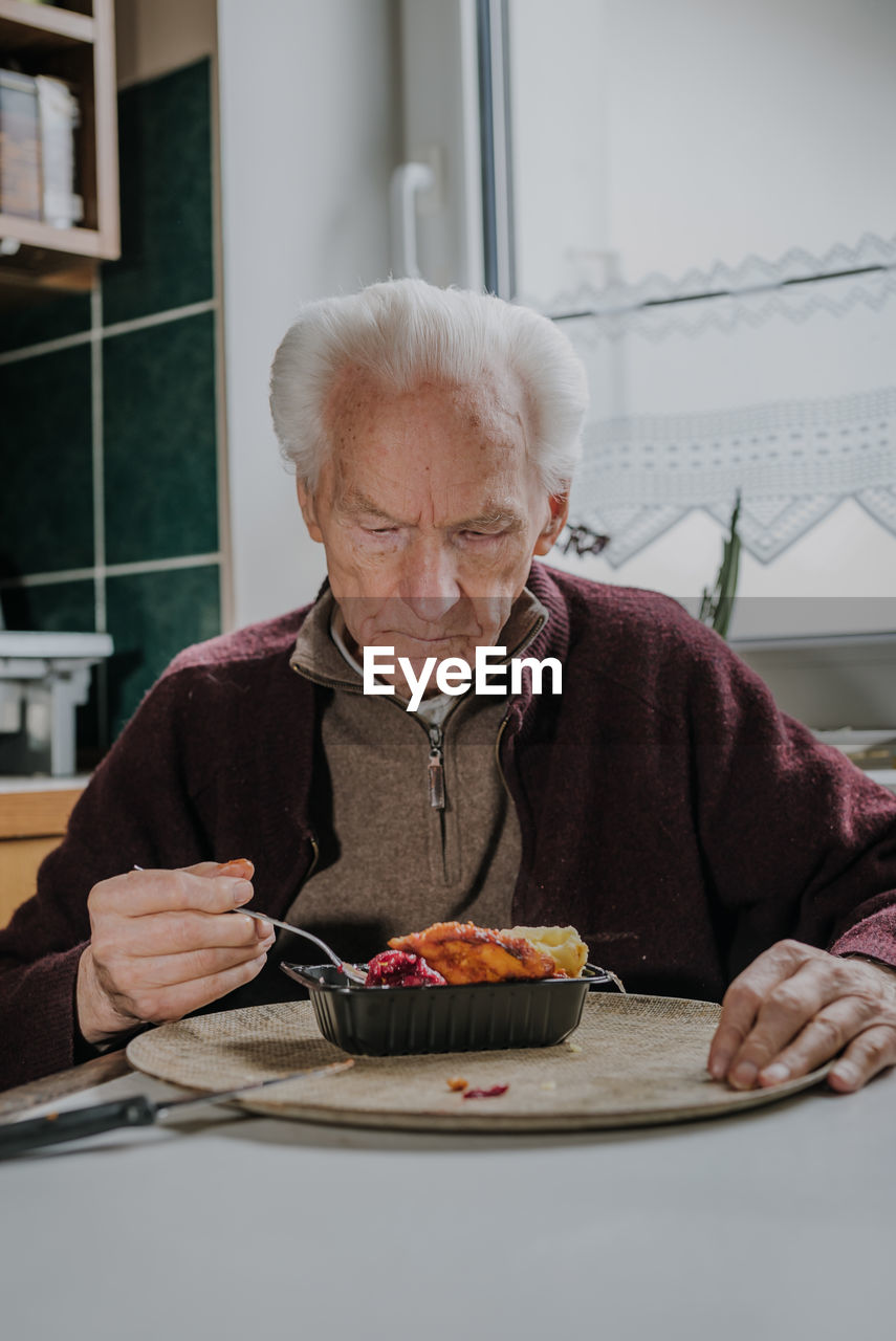 Senior man eating food at home