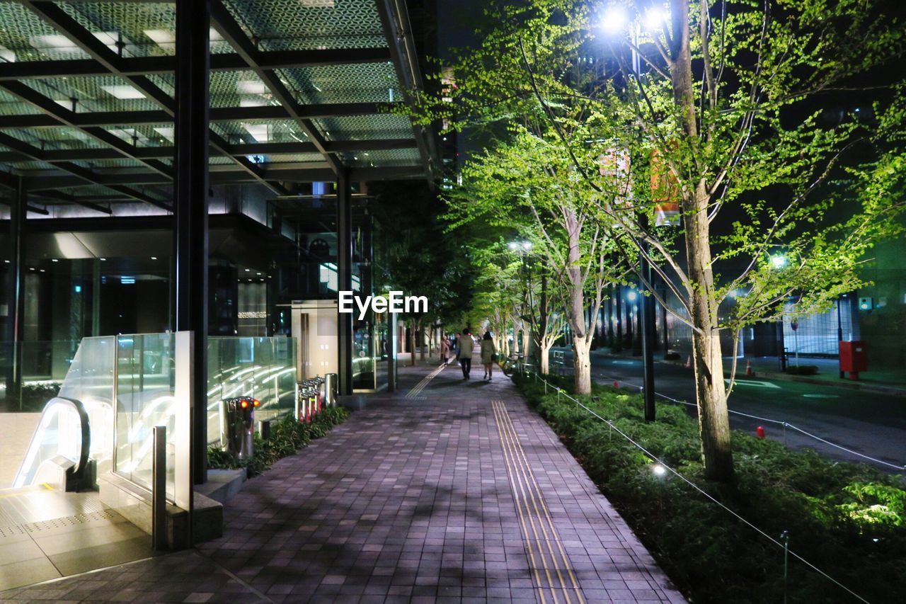 Distant view of people walking on footpath in city at night