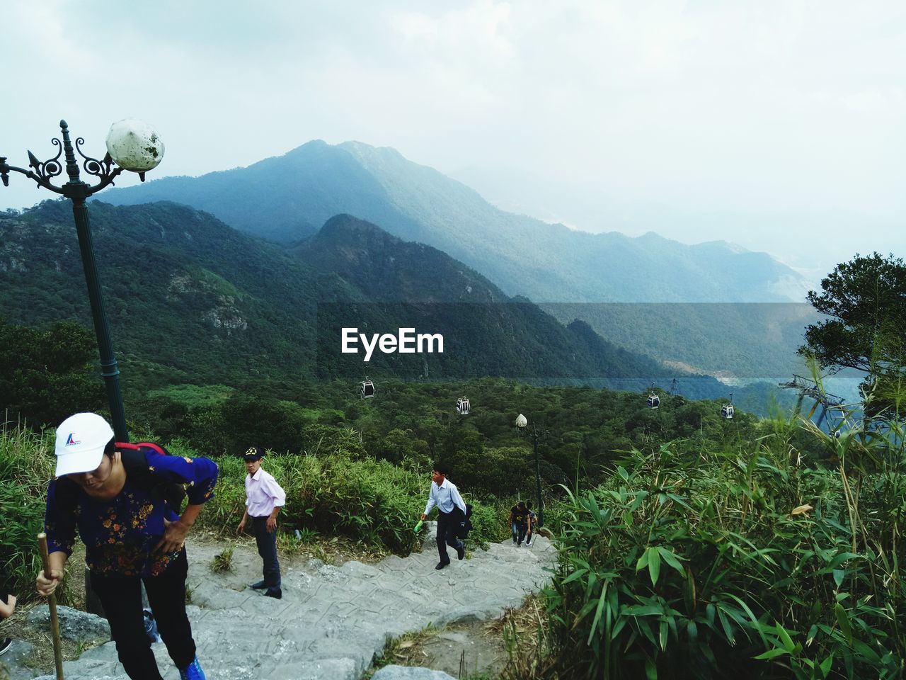 REAR VIEW OF PEOPLE WALKING ON MOUNTAIN ROAD