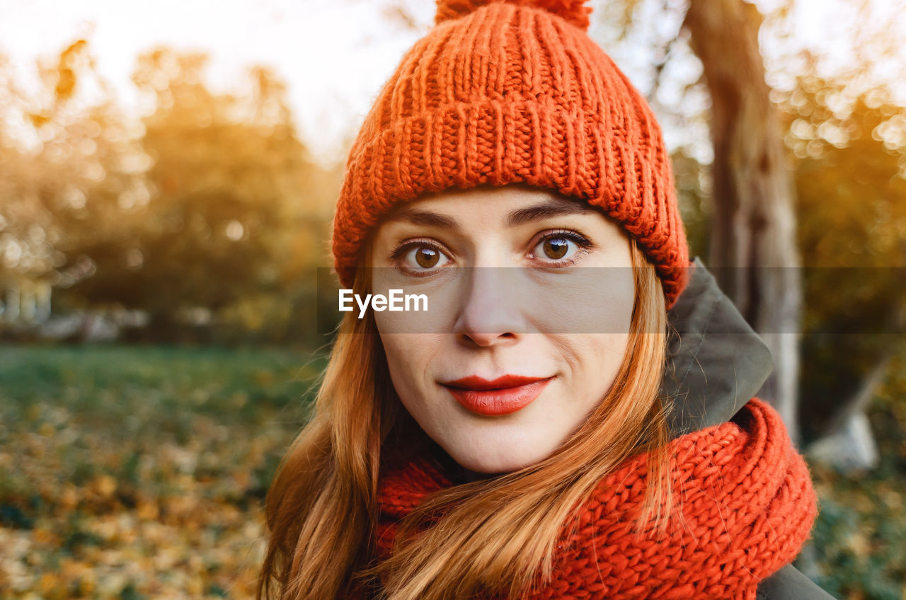 Autumn fashion portrait of stylish woman in bright orange knitted hat and scarf. red hair