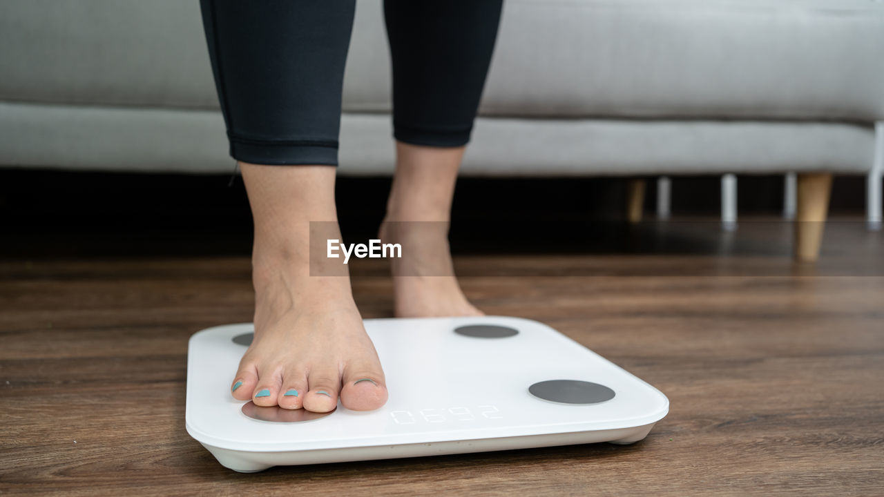 human leg, limb, one person, indoors, shoe, adult, footwear, low section, barefoot, women, lifestyles, home interior, domestic life, standing, young adult, human limb, domestic room, relaxation, flooring, living room, white, human foot, clothing, close-up, focus on foreground, hardwood floor, wood, toe, leisure activity, furniture