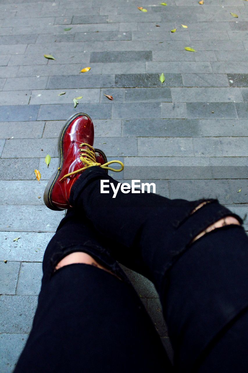 LOW SECTION OF MAN WEARING SHOES ON FLOOR