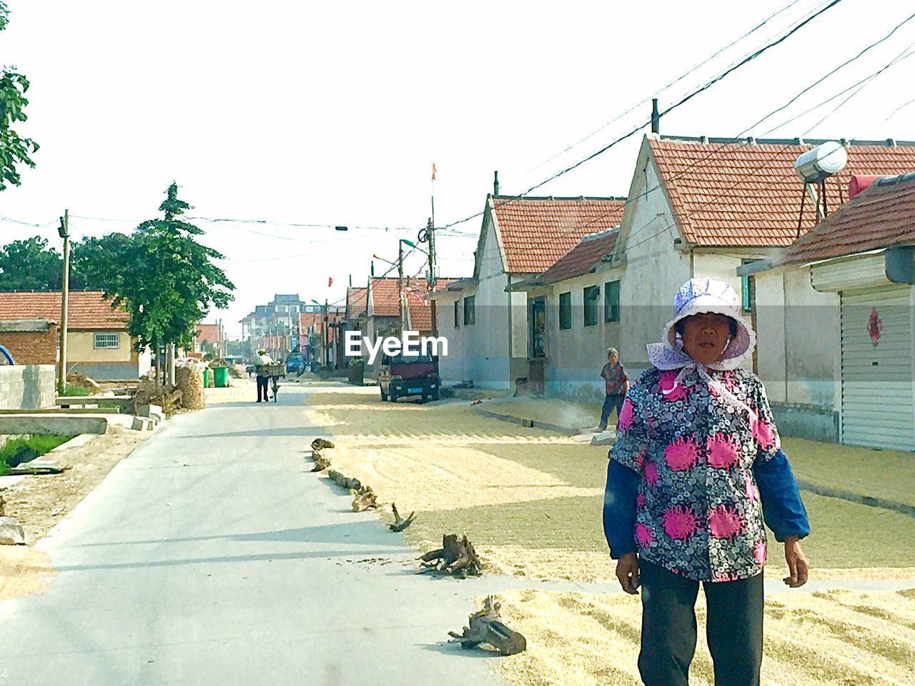 WOMAN STANDING ON STREET AGAINST BUILDING