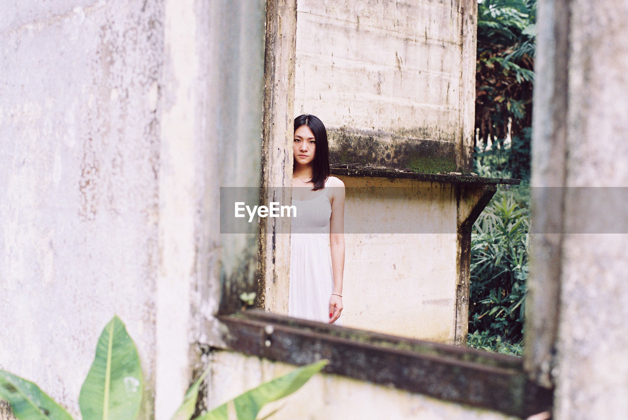 Portrait of young woman looking through window