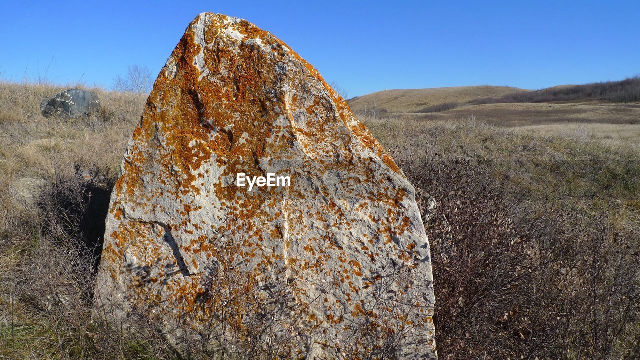 View of rock formation on field against sky