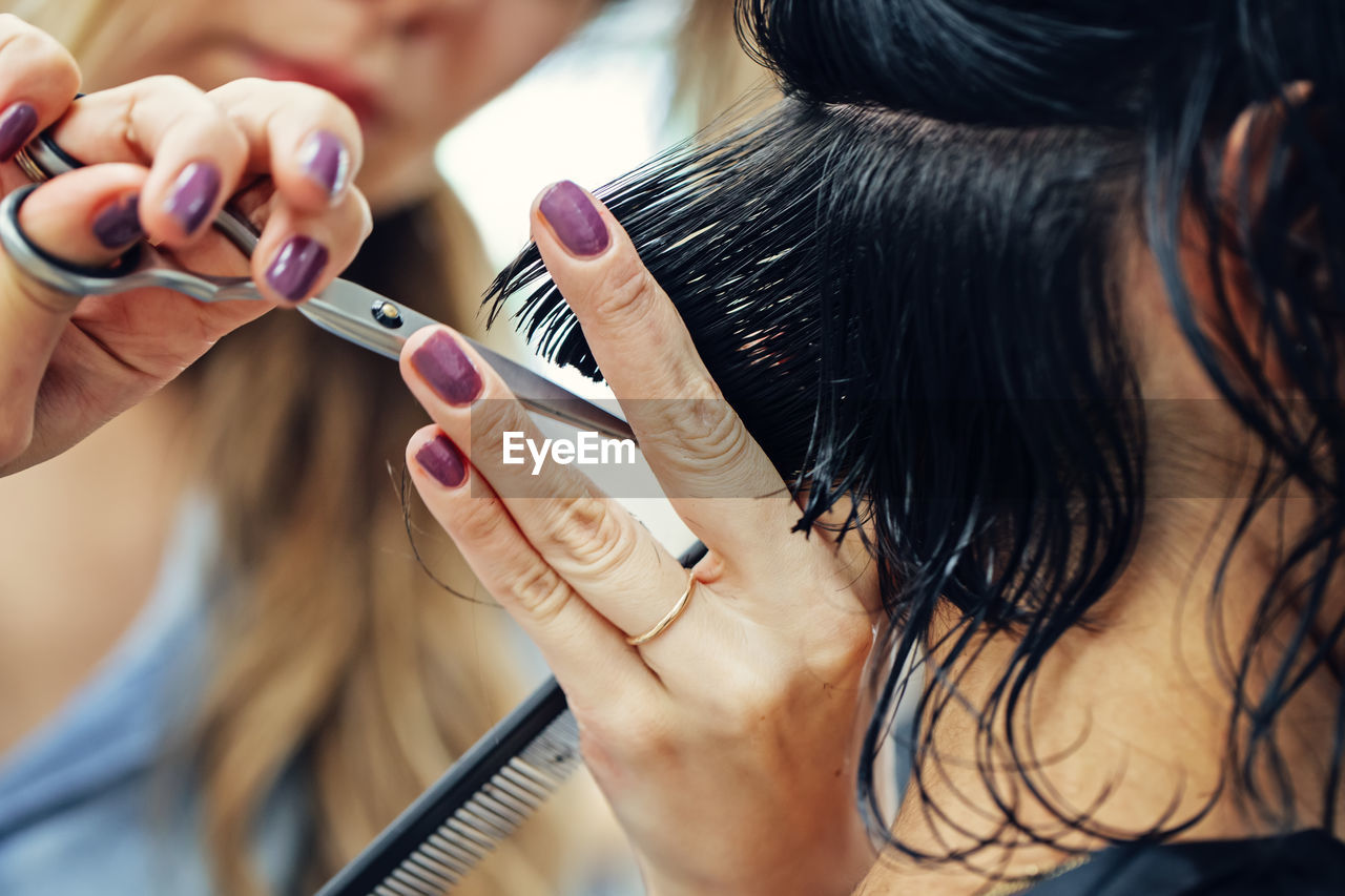 Cropped hands of hairdresser cutting hair in salon