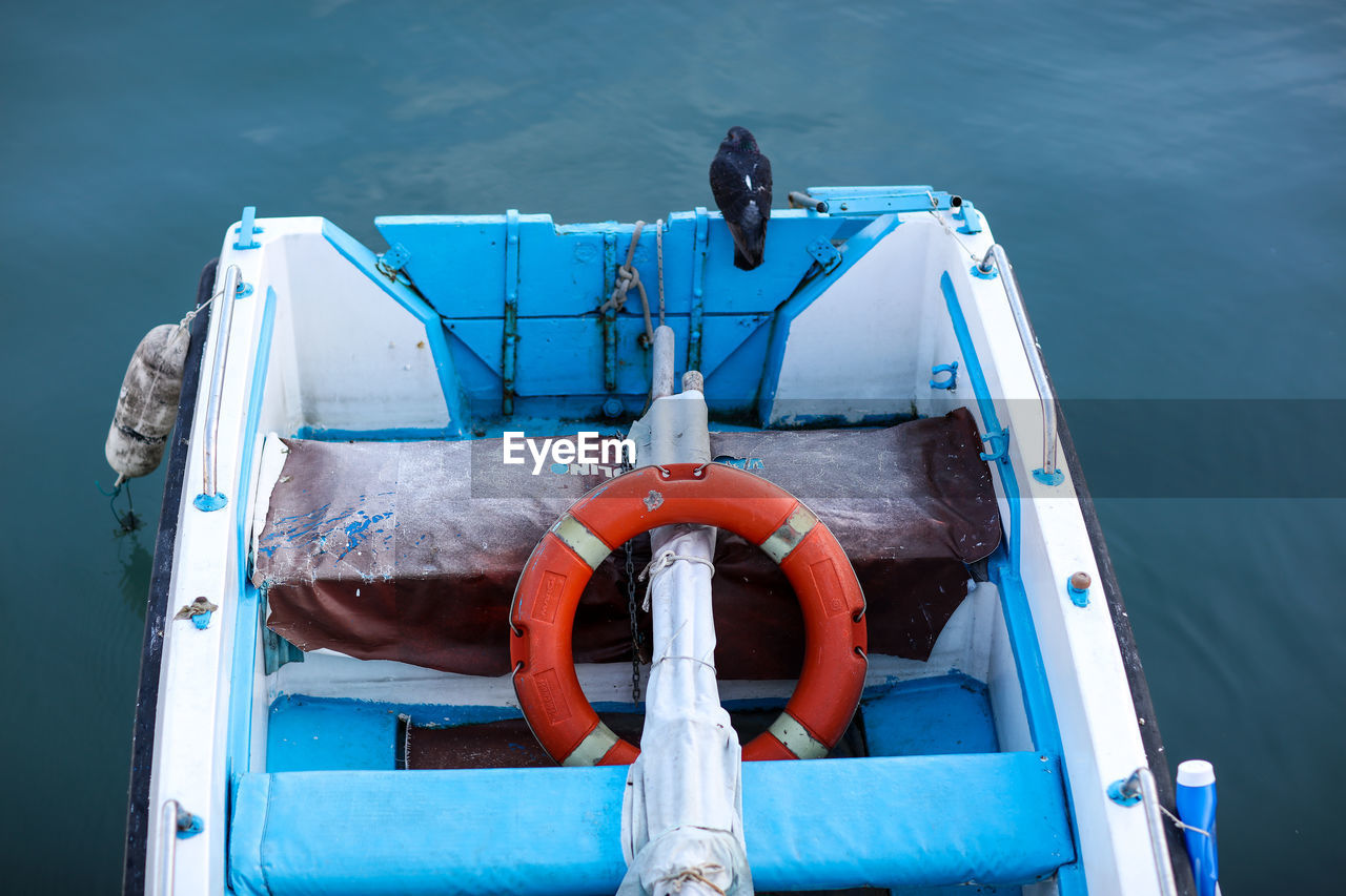 High angle view of boat deck in sea while bird perching