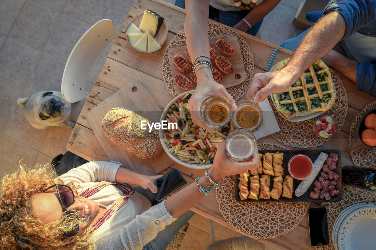 High angle view of friends toasting drinks while having food at table