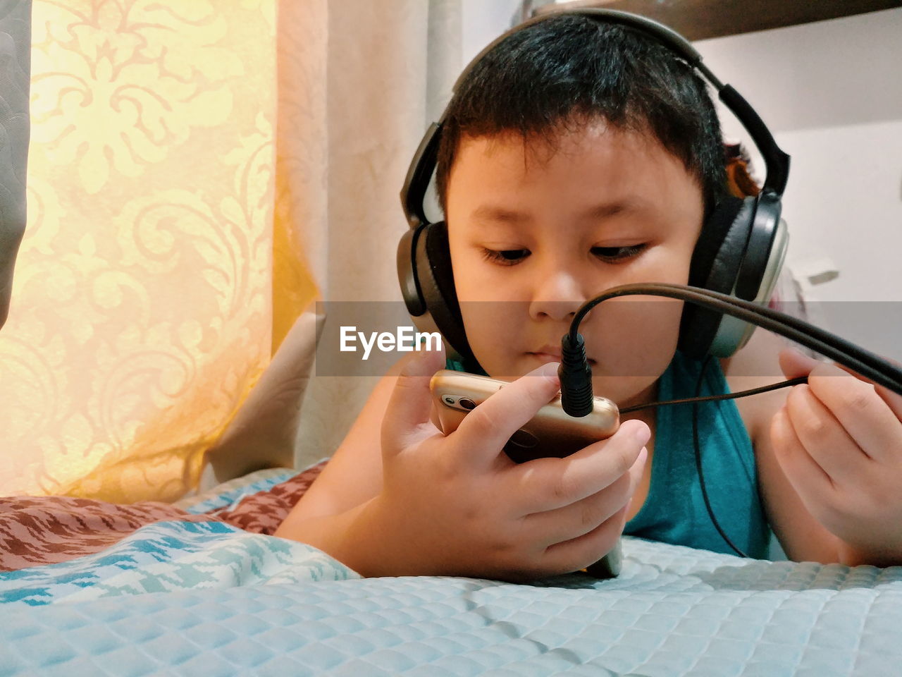 Close-up of boy using mobile phone while listening to headphones