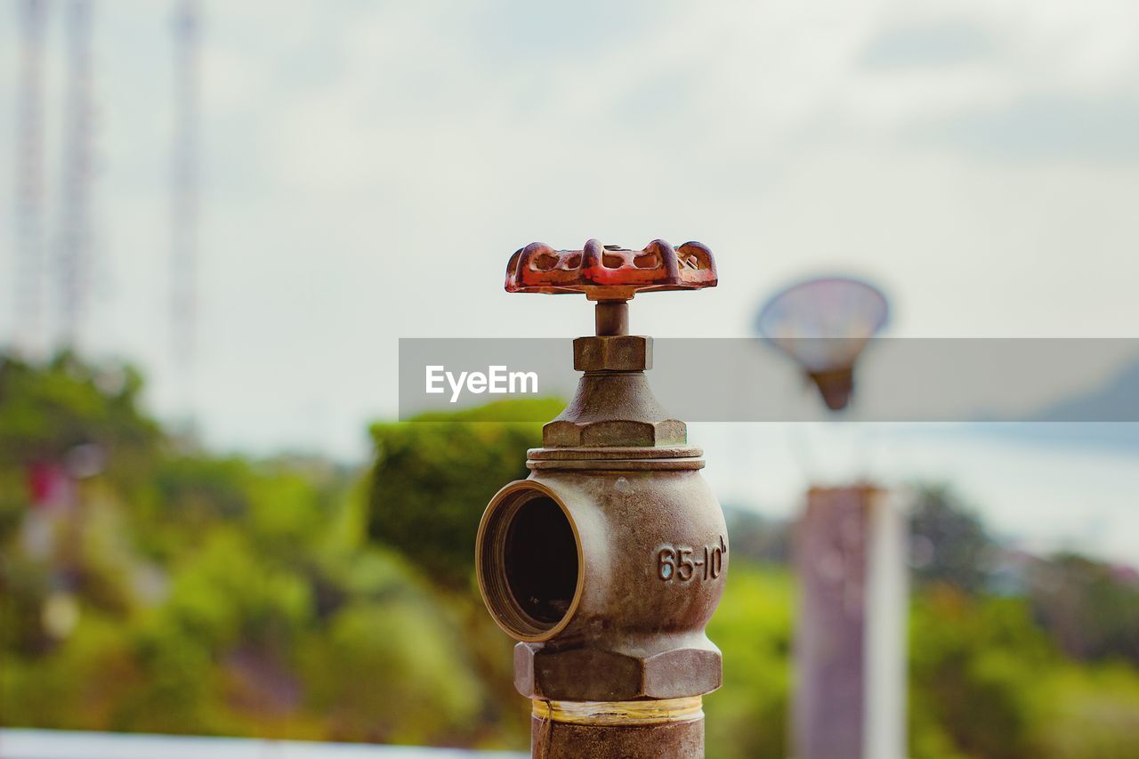 CLOSE-UP OF FIRE HYDRANT AGAINST RUSTY METAL AGAINST SKY