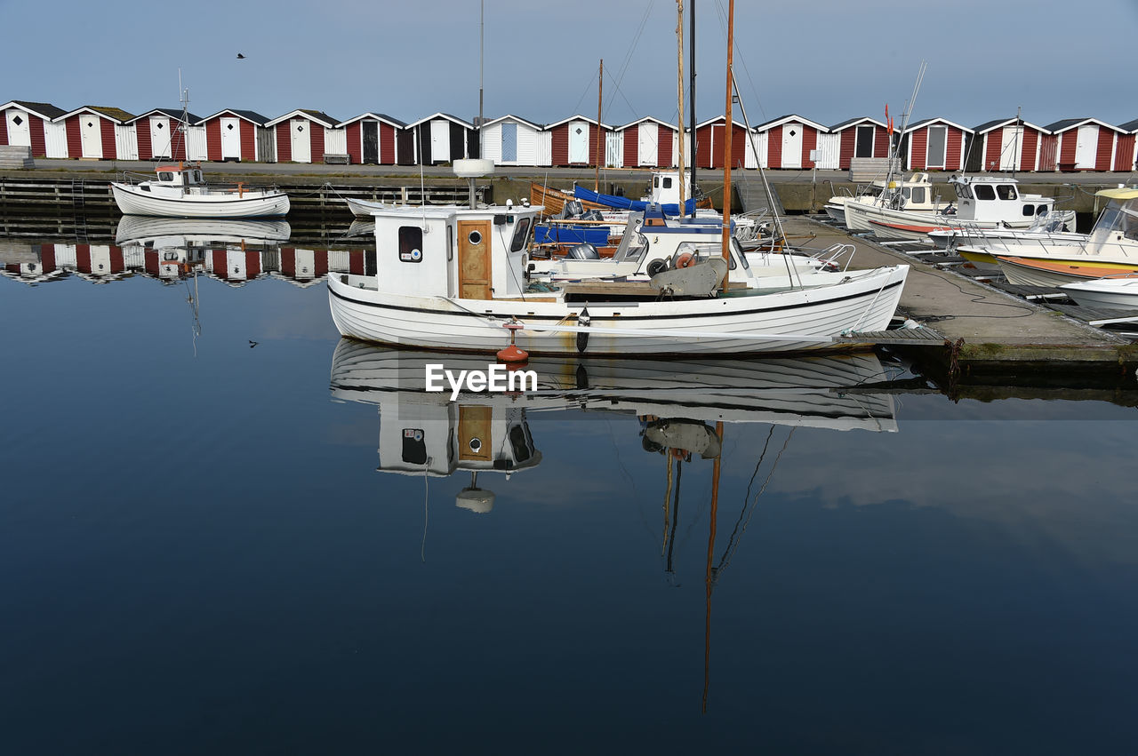 Boats moored at harbor against clear sky