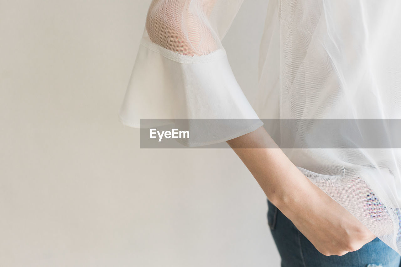 Midsection of woman standing against white background