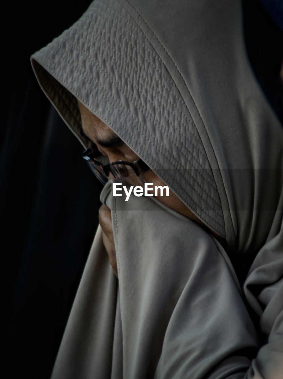 Close-up of mature woman in hijab against black background