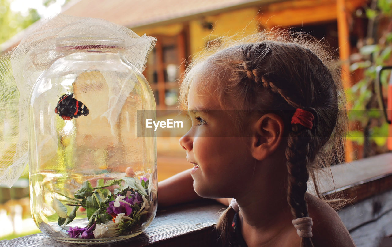 Close-up of girl looking at butterfly in jar