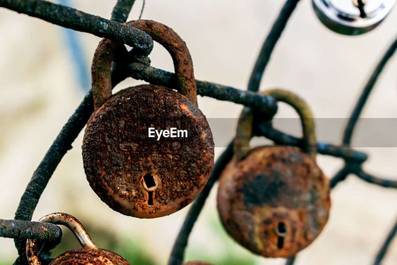 close-up of padlock hanging on chainlink fence