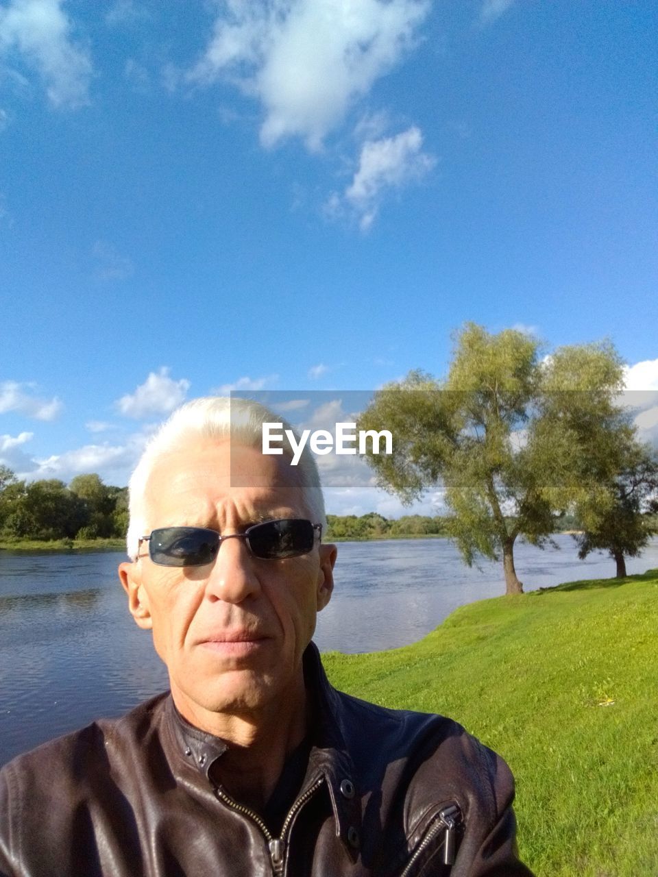 Portrait of man wearing sunglasses by river against sky