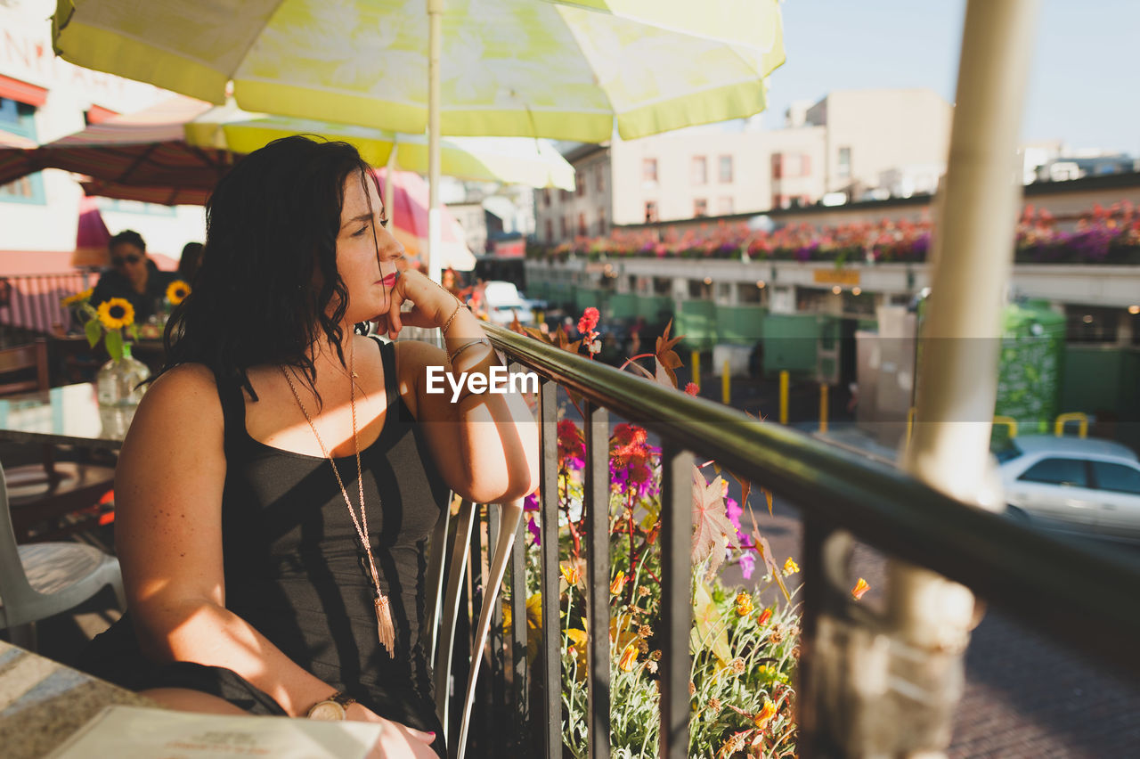 Thoughtful young woman leaning on railing in restaurant