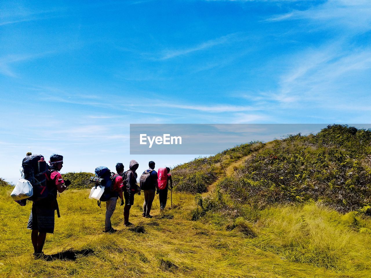 GROUP OF PEOPLE WALKING ON MOUNTAIN AGAINST SKY