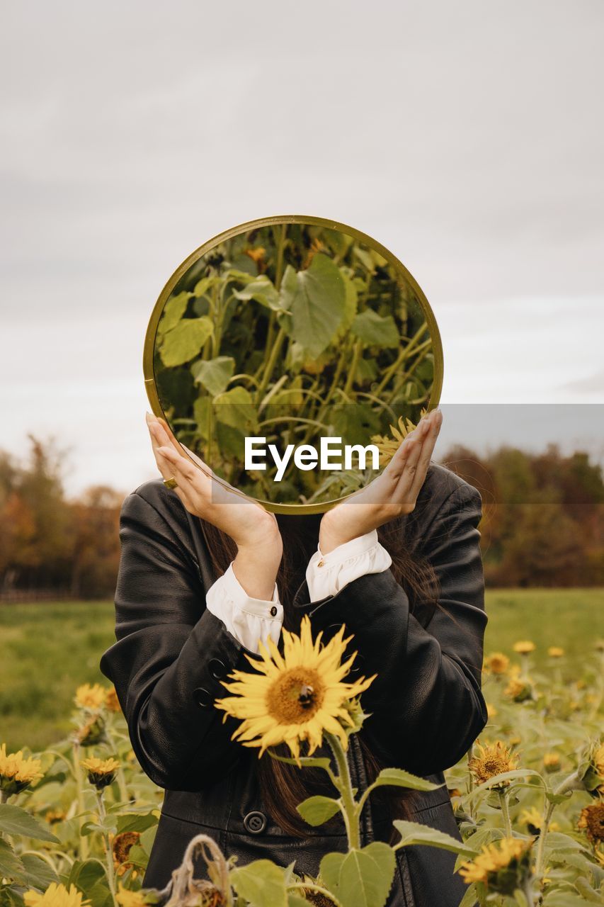 Close-up of person holding mirror on field