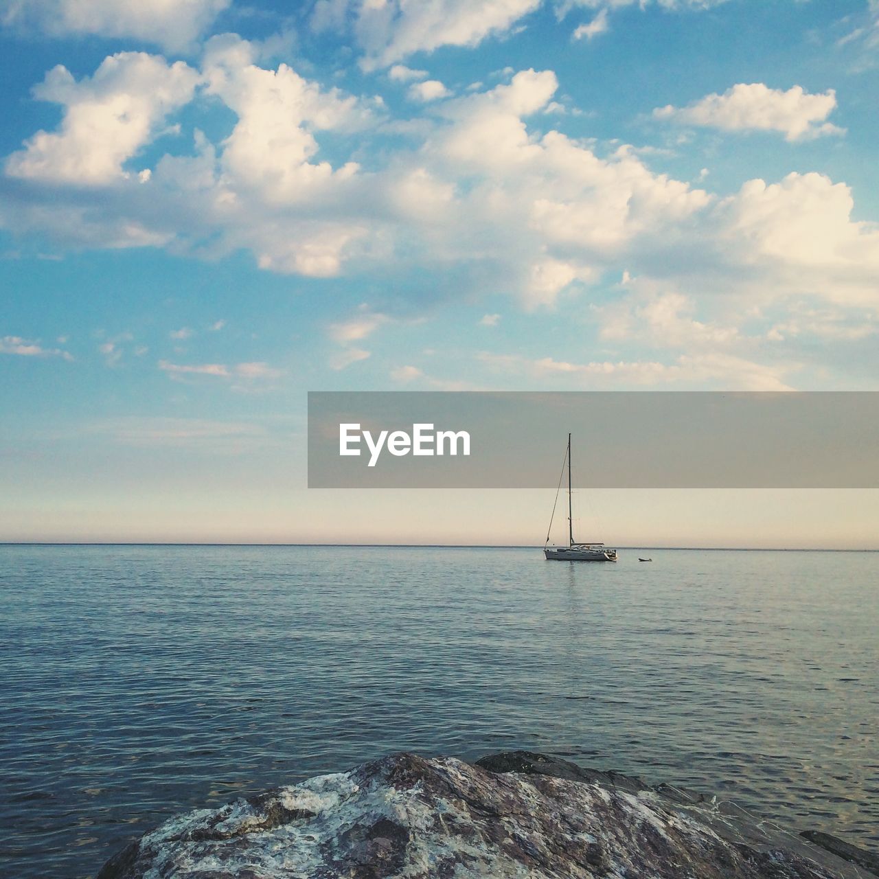 Sailboat sailing in sea against cloudy sky