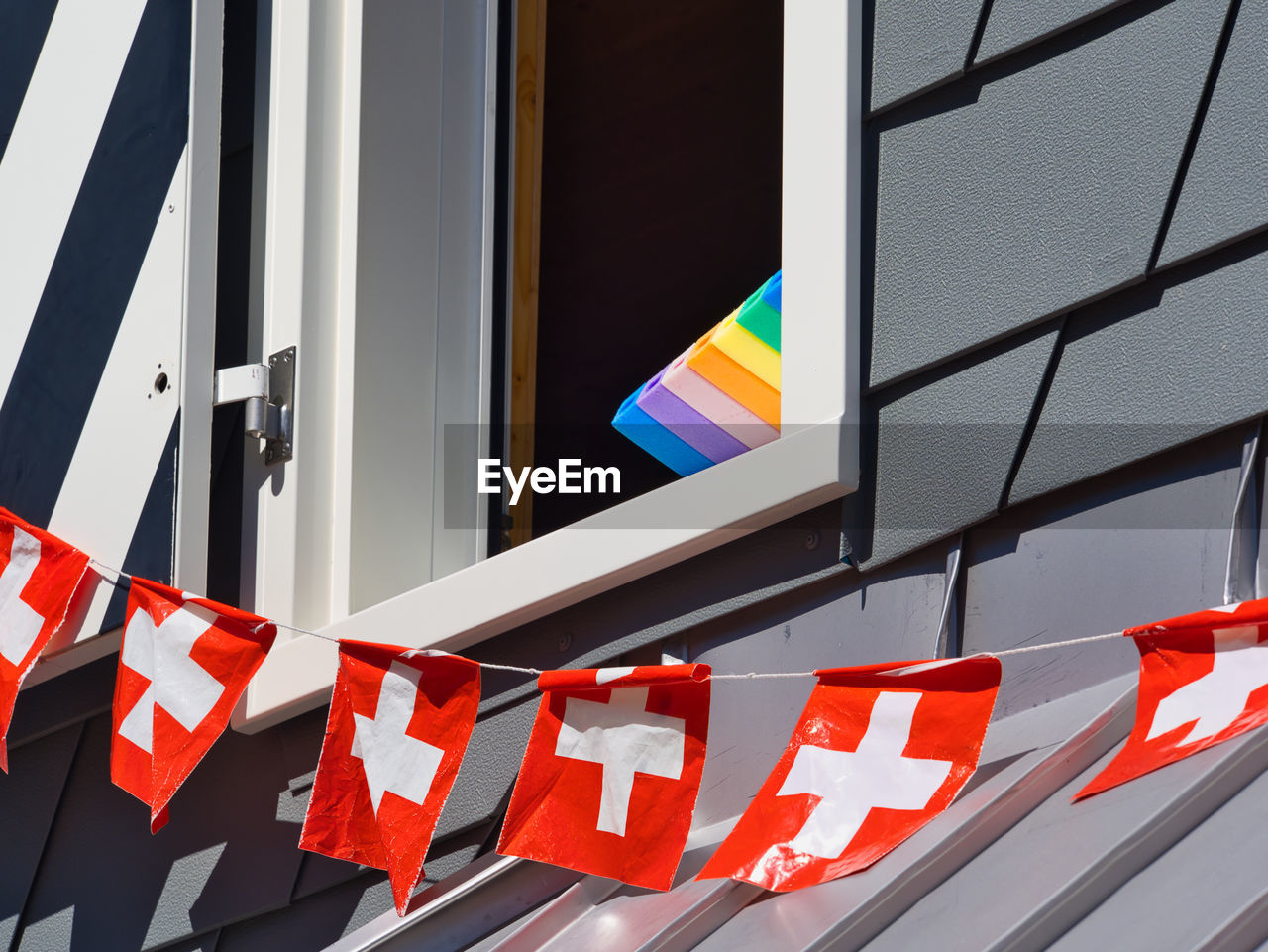 Low angle view of swiss flags by window 