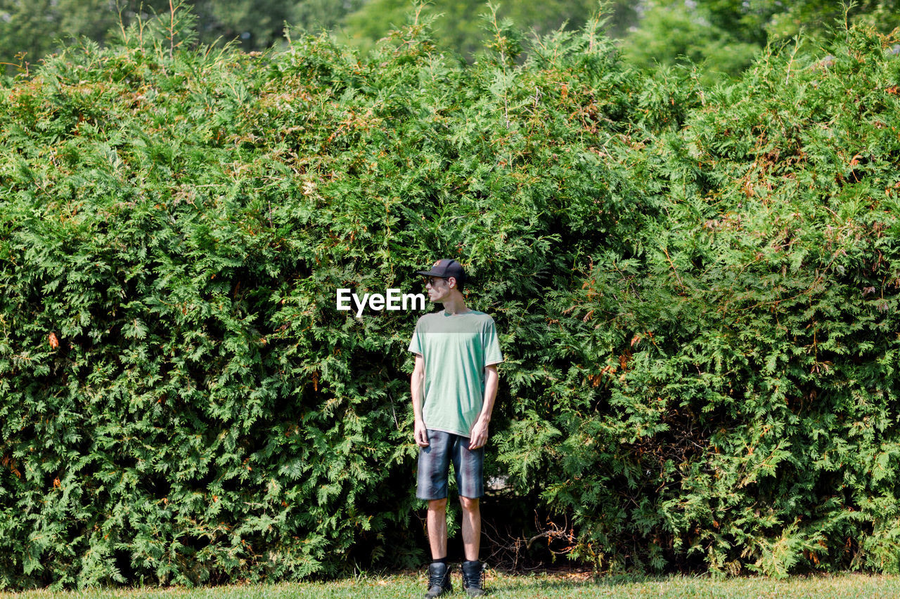 Full length of young man standing against plants