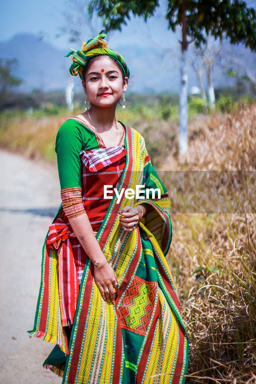 Portrait of young woman in traditional clothes standing outdoors