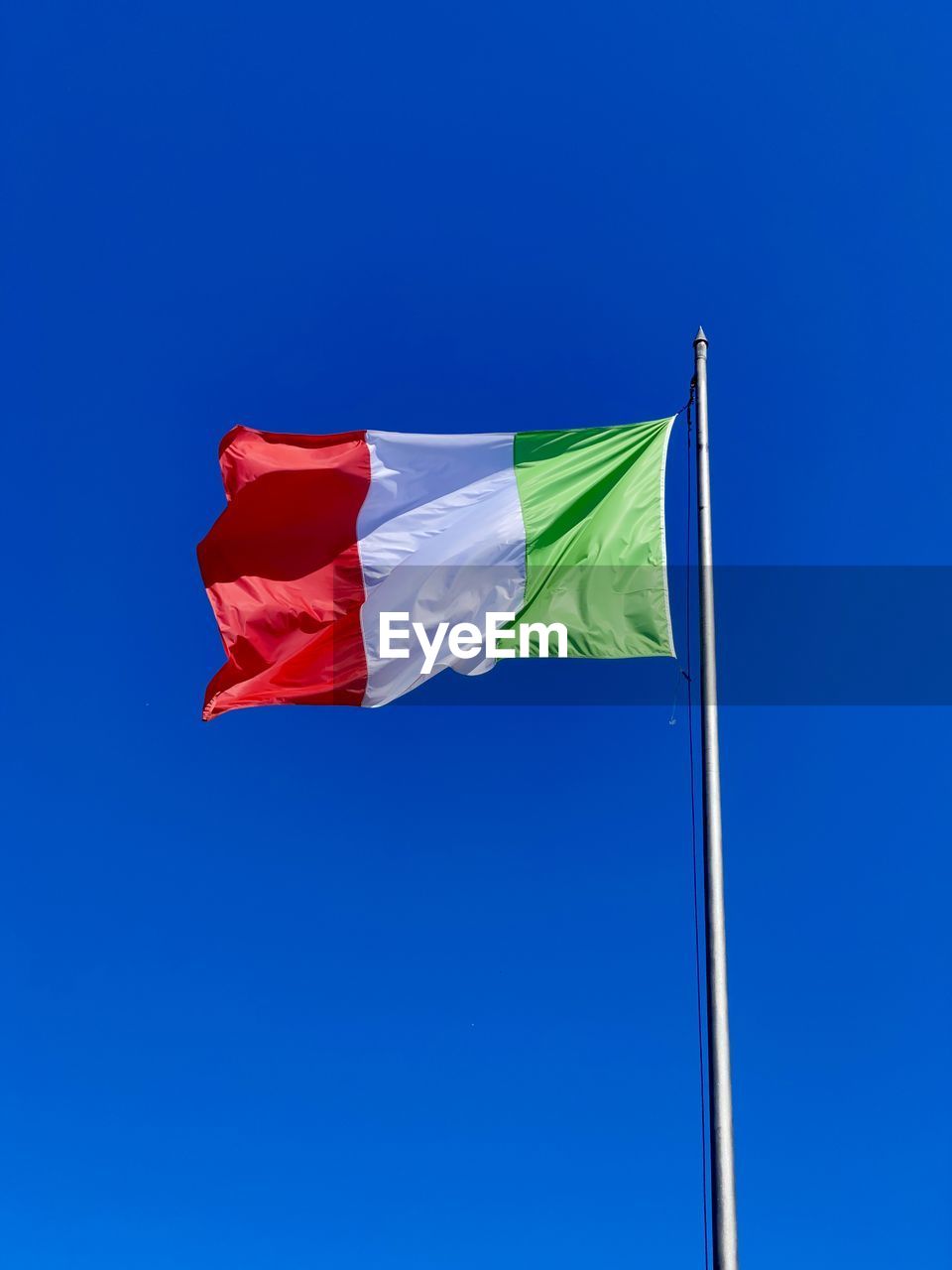 Low angle view of flag against clear blue sky