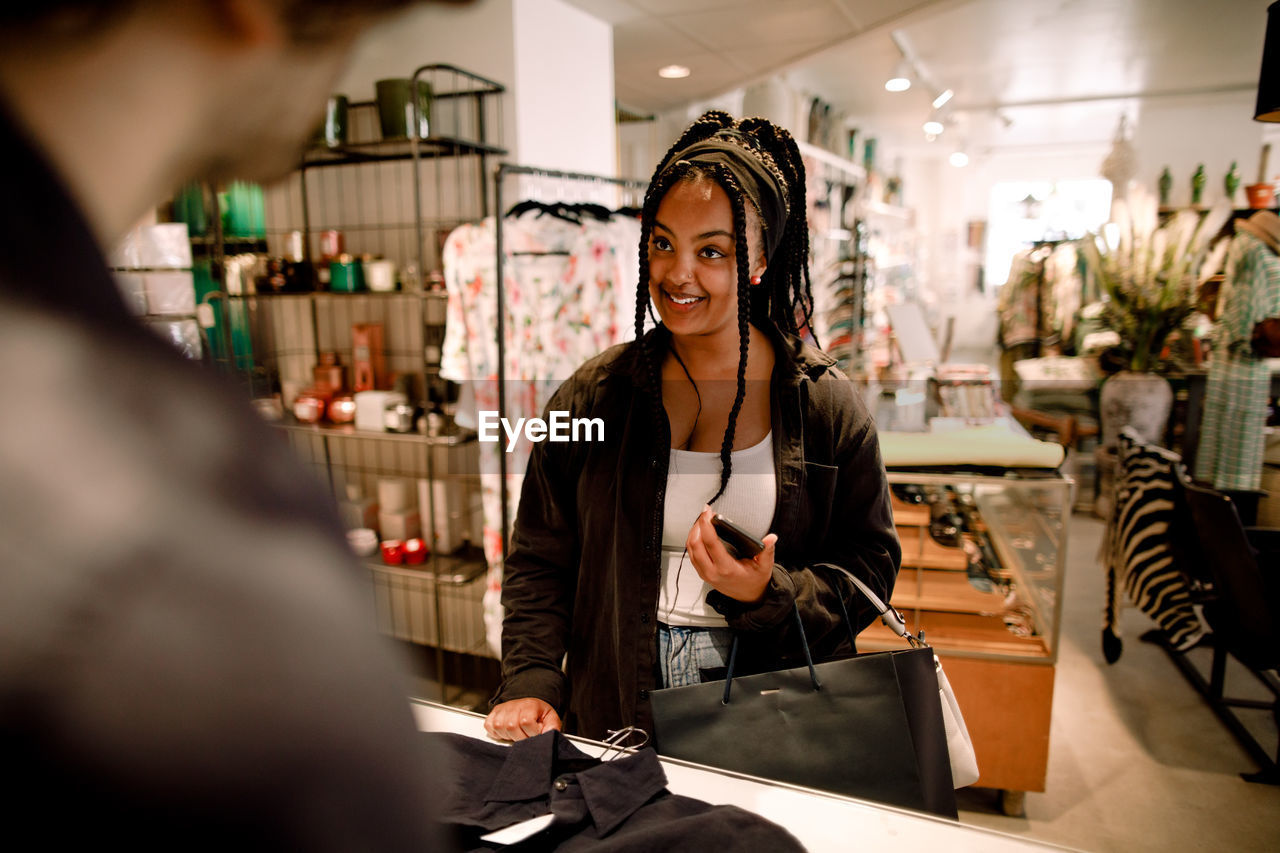 Smiling customer talking to salesman at fashion store