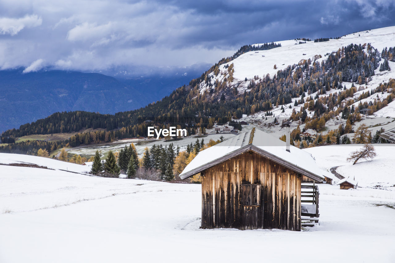 House on snowcapped mountains against cloudy sky