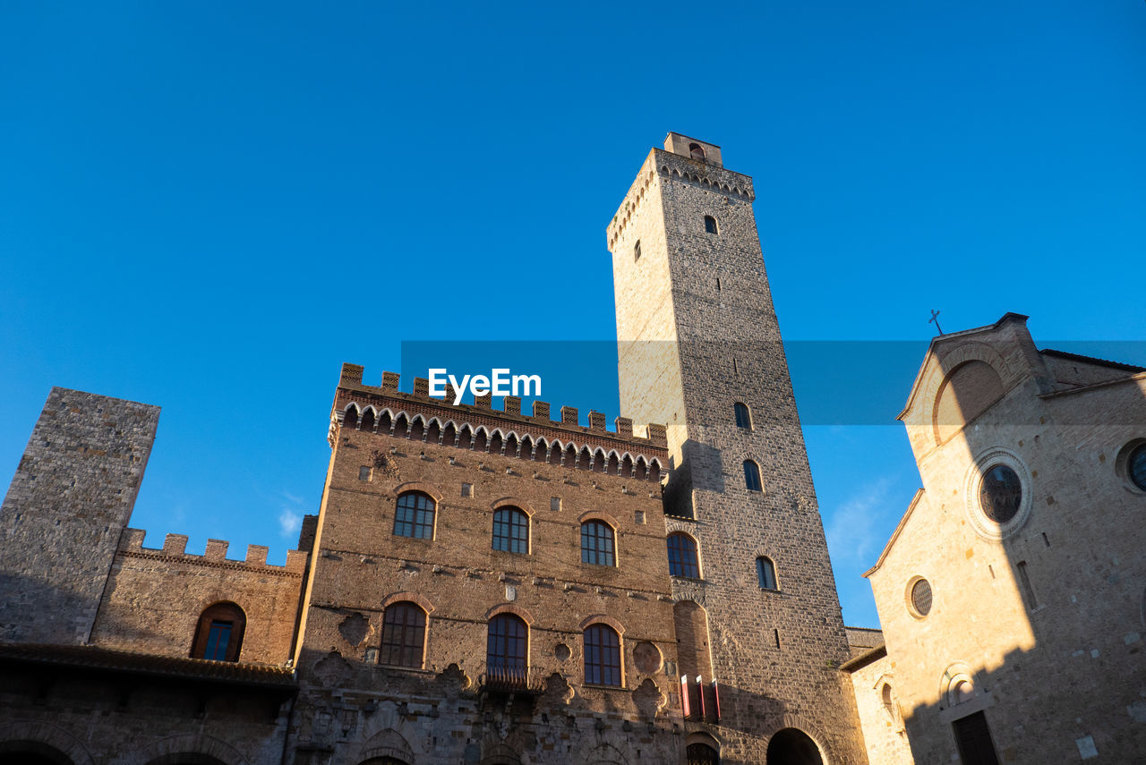 Ncient buildings in the main square of city of san gimignano in early morning, tuscany