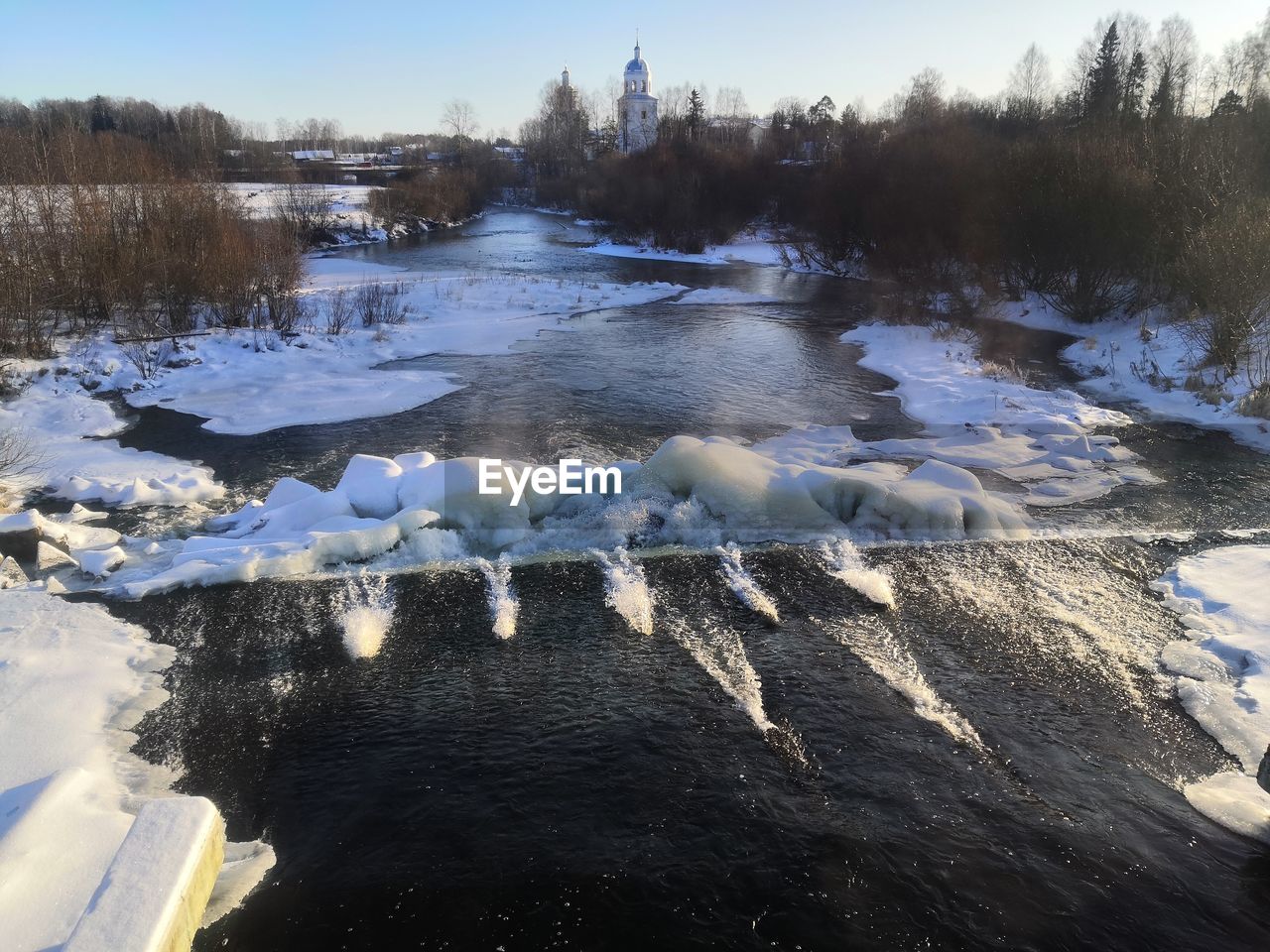 FROZEN RIVER AMIDST TREES AGAINST SKY