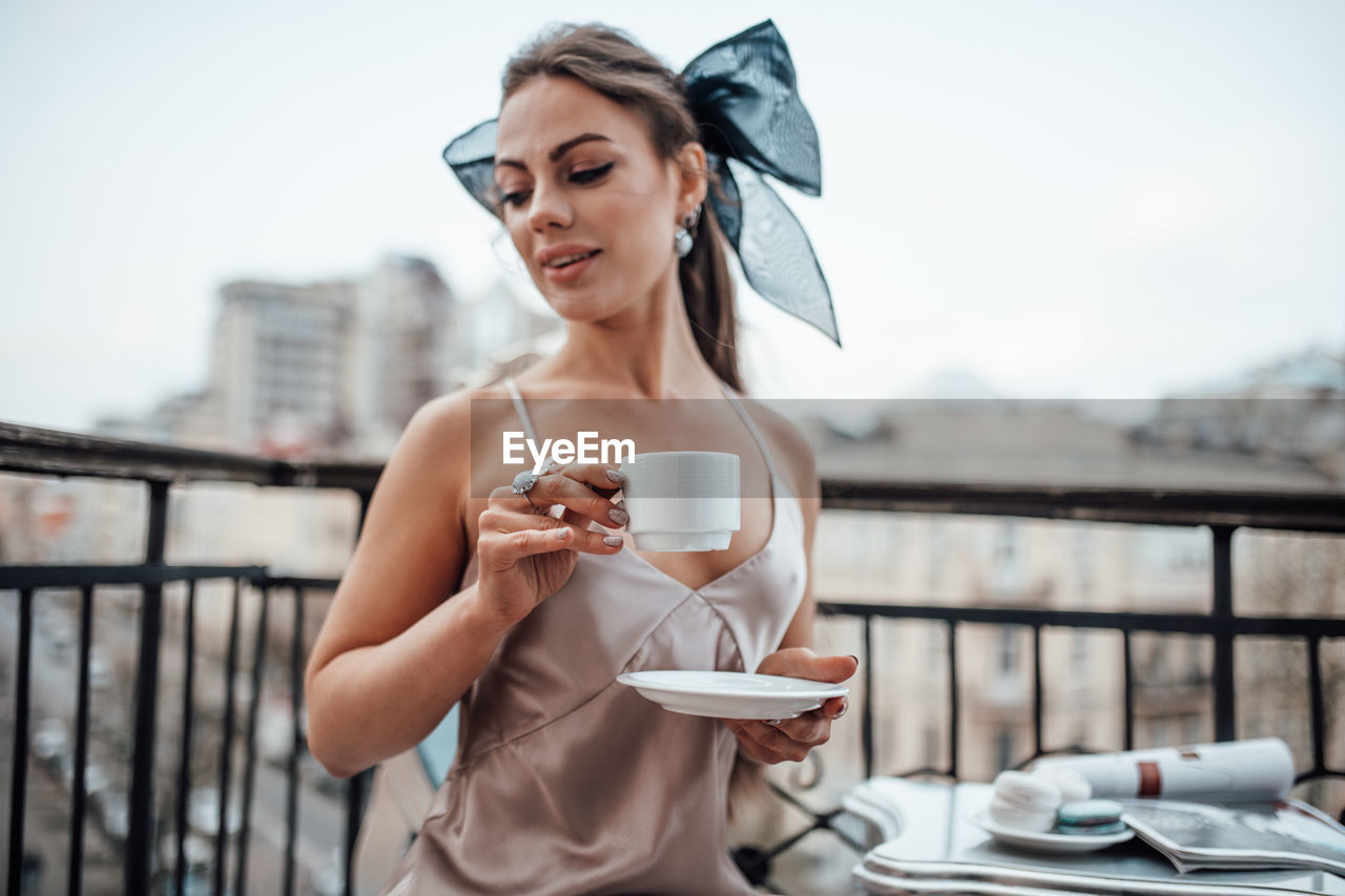 Young woman drinking coffee on railing