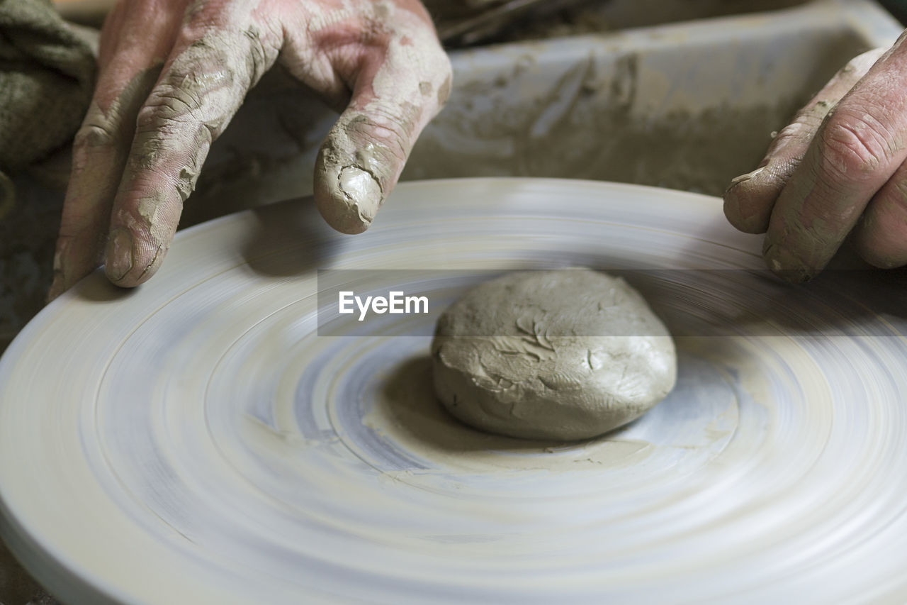 Cropped hand of potter using pottery wheel