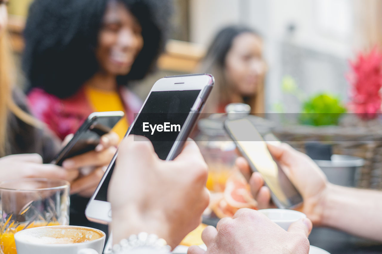 Group of people using smart phones at dining table