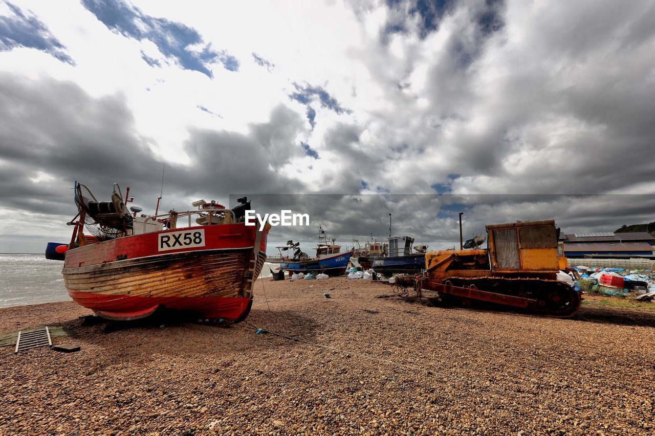 Boats moored in sea against cloudy sky