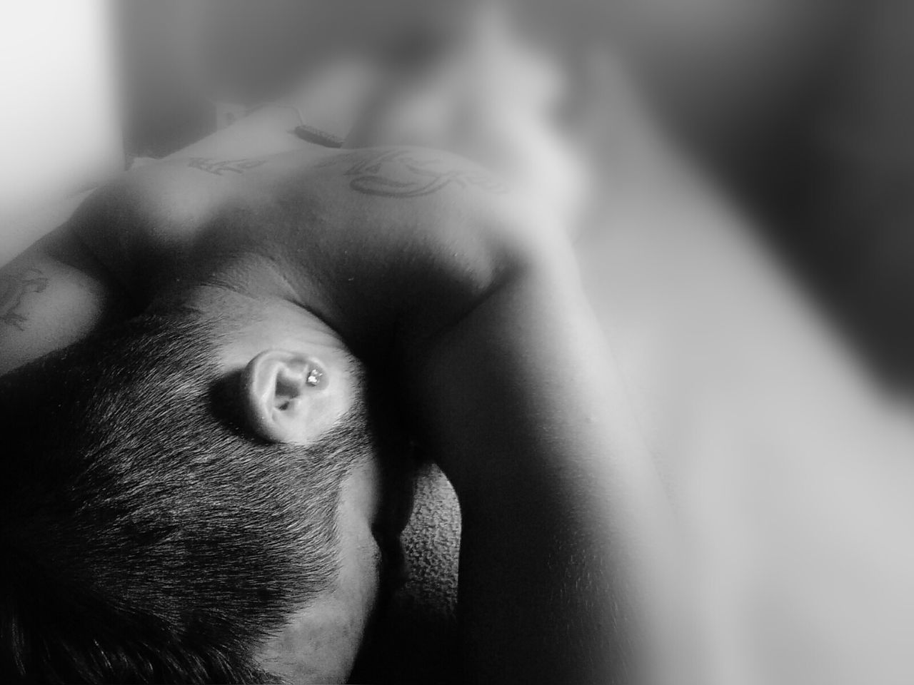 Rear view of shirtless man with tattoos lying on bed