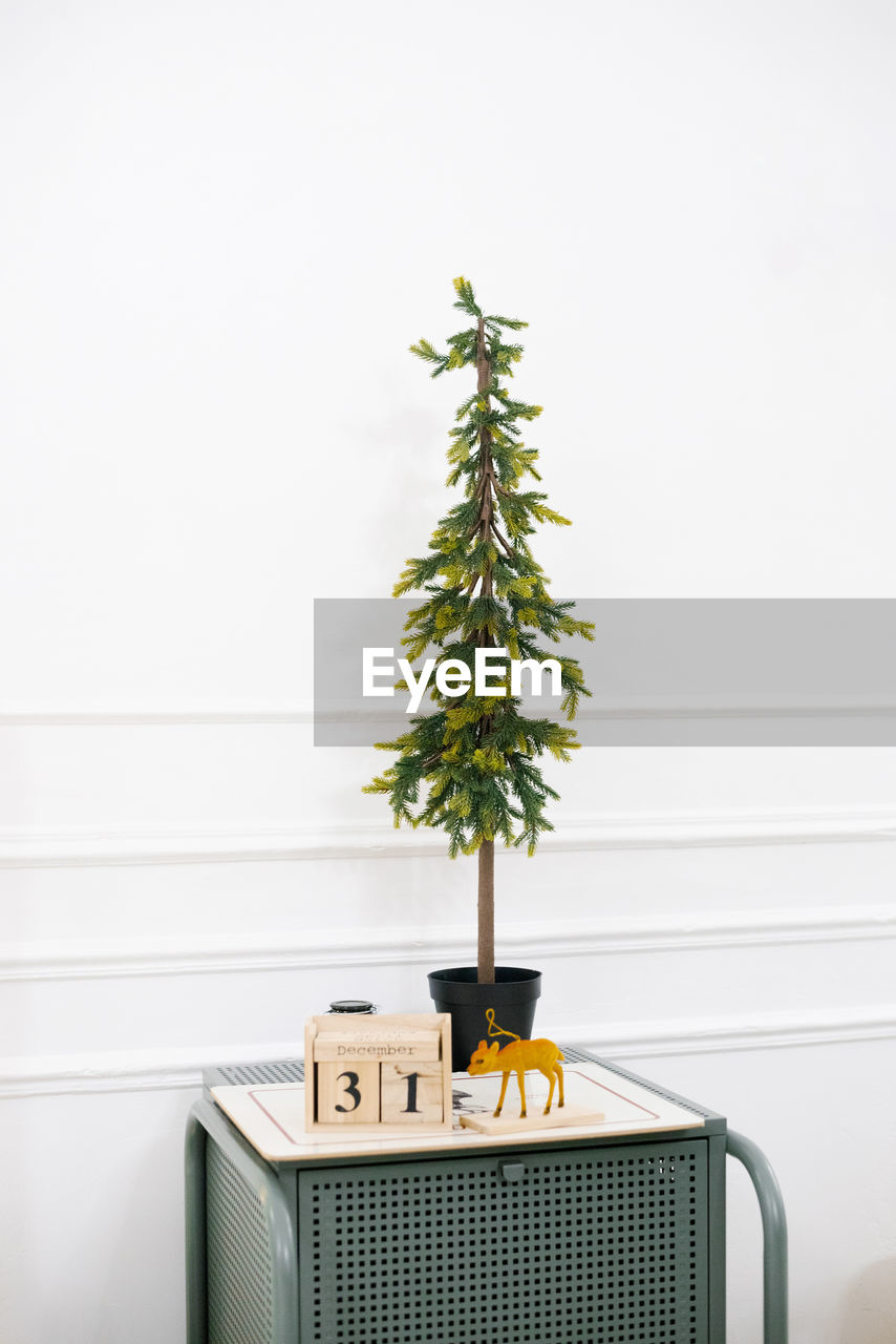 Decorative christmas tree stands on the bedside table in the bedroom decorated for the new year