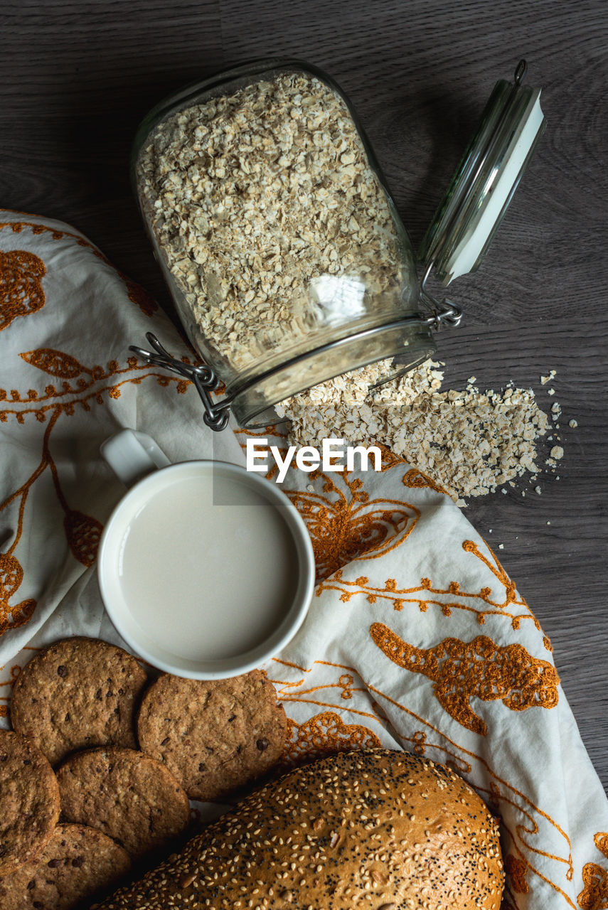 Top view of breakfast with bread, milk, cookies and oatmeal.