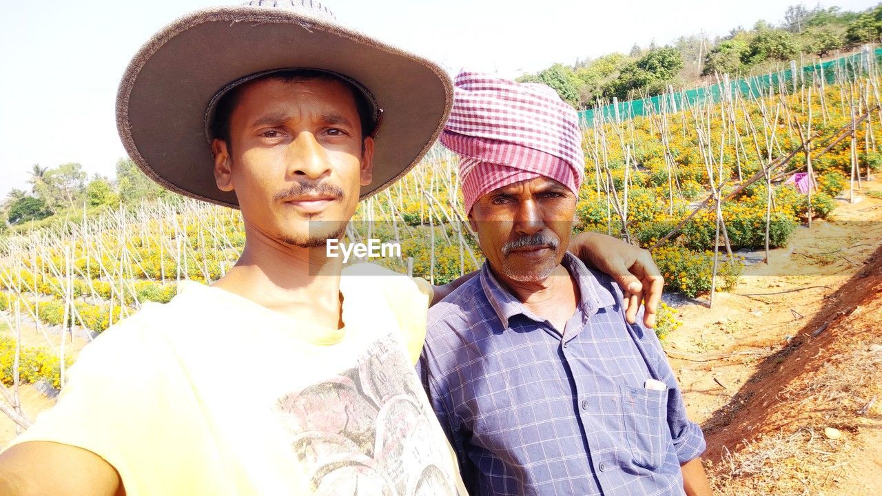 adult, two people, men, hat, agriculture, rural scene, landscape, nature, portrait, crop, smiling, plant, togetherness, farm, emotion, farmer, field, person, happiness, clothing, occupation, human face, women, land, growth, day, working, looking at camera, sunlight, straw hat, casual clothing, lifestyles, outdoors, young adult, summer, sun hat, positive emotion, food and drink, female, sky, front view, bonding, business, food, waist up