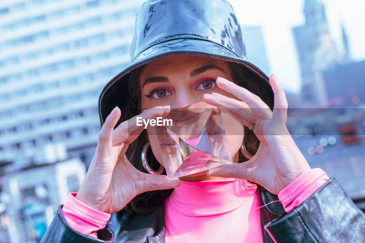 Portrait of young woman holding crystal in city