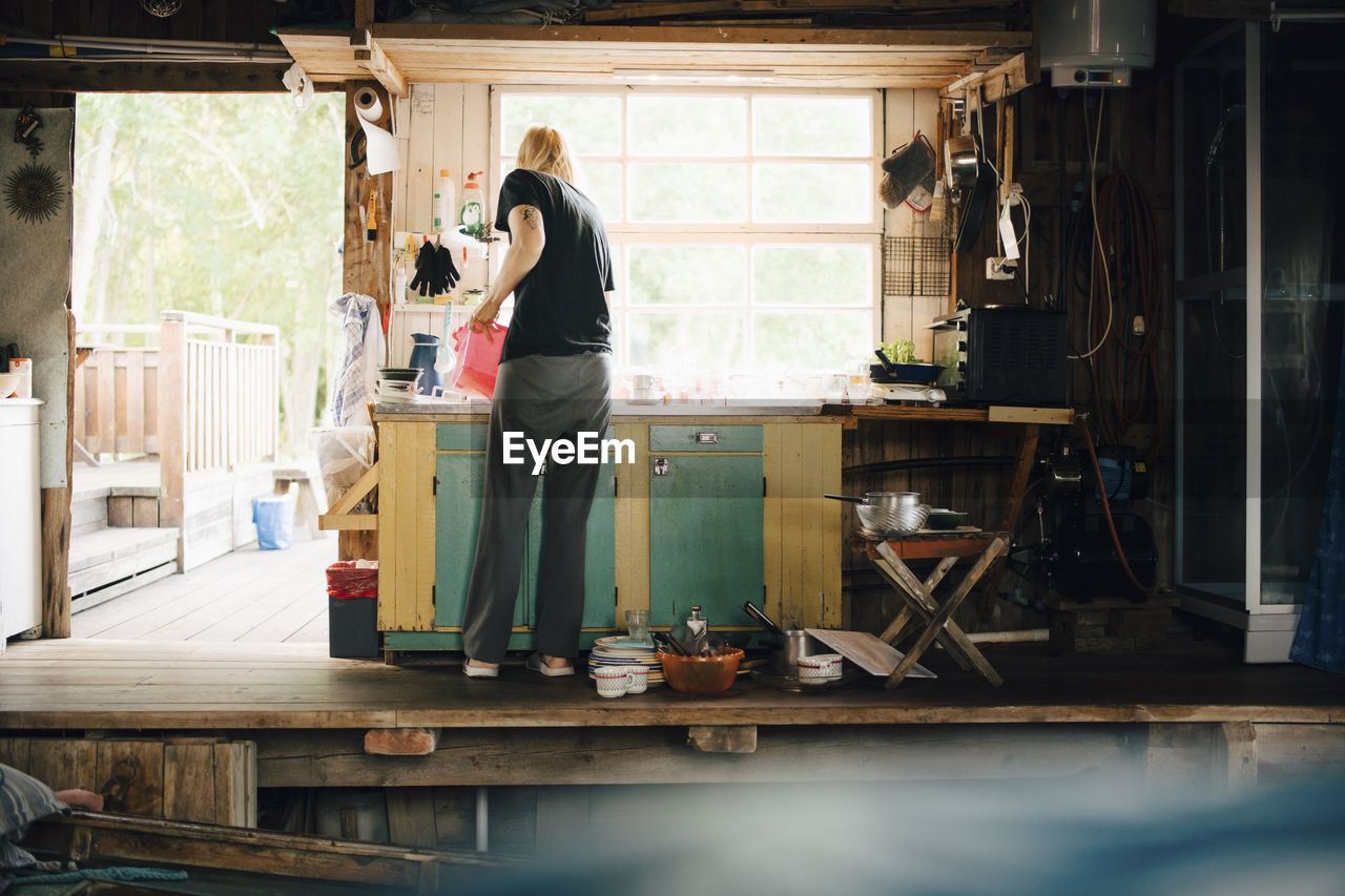 Full length rear view of woman washing dishes at summer house