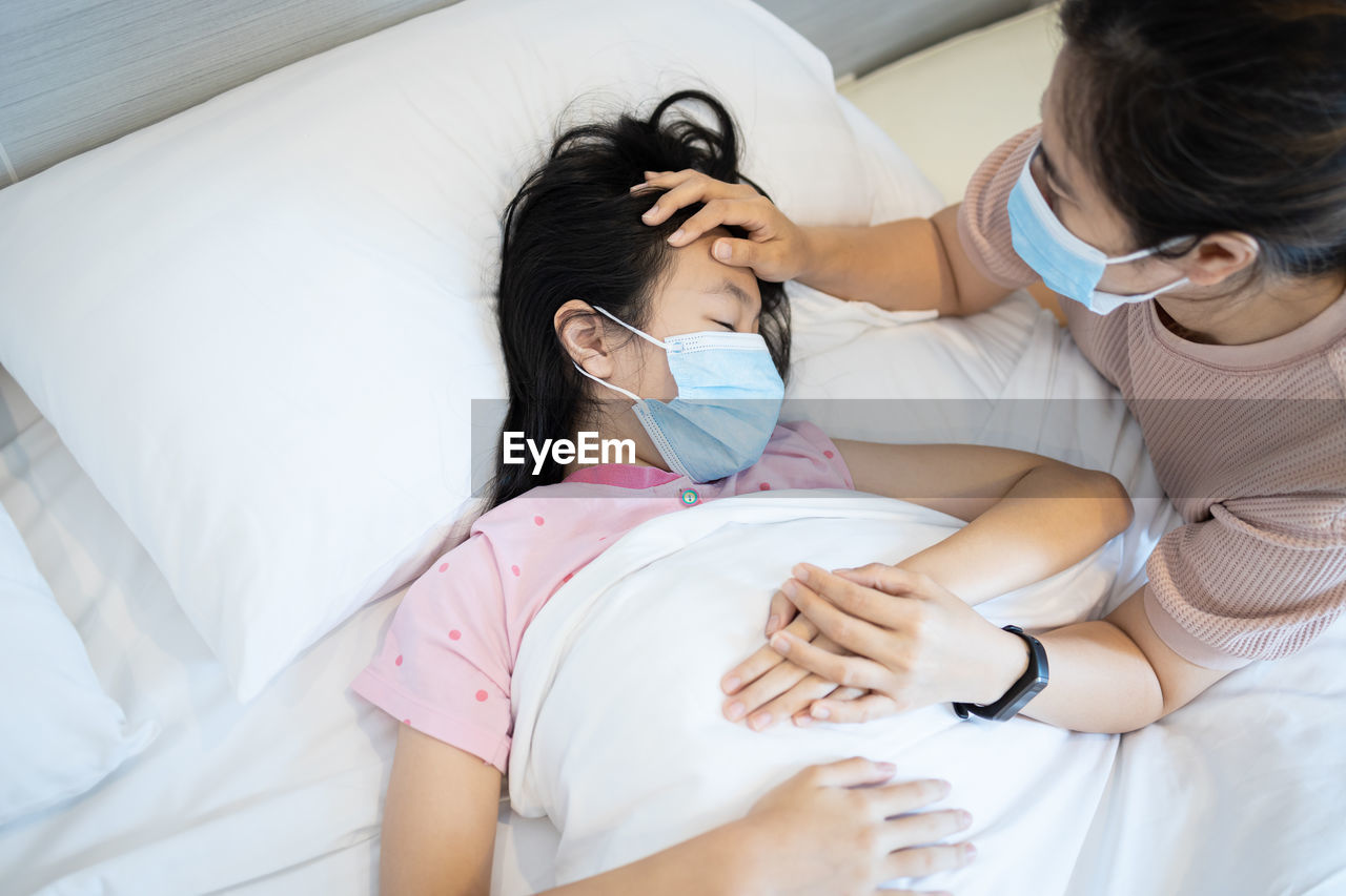 High angle view of friends lying on bed