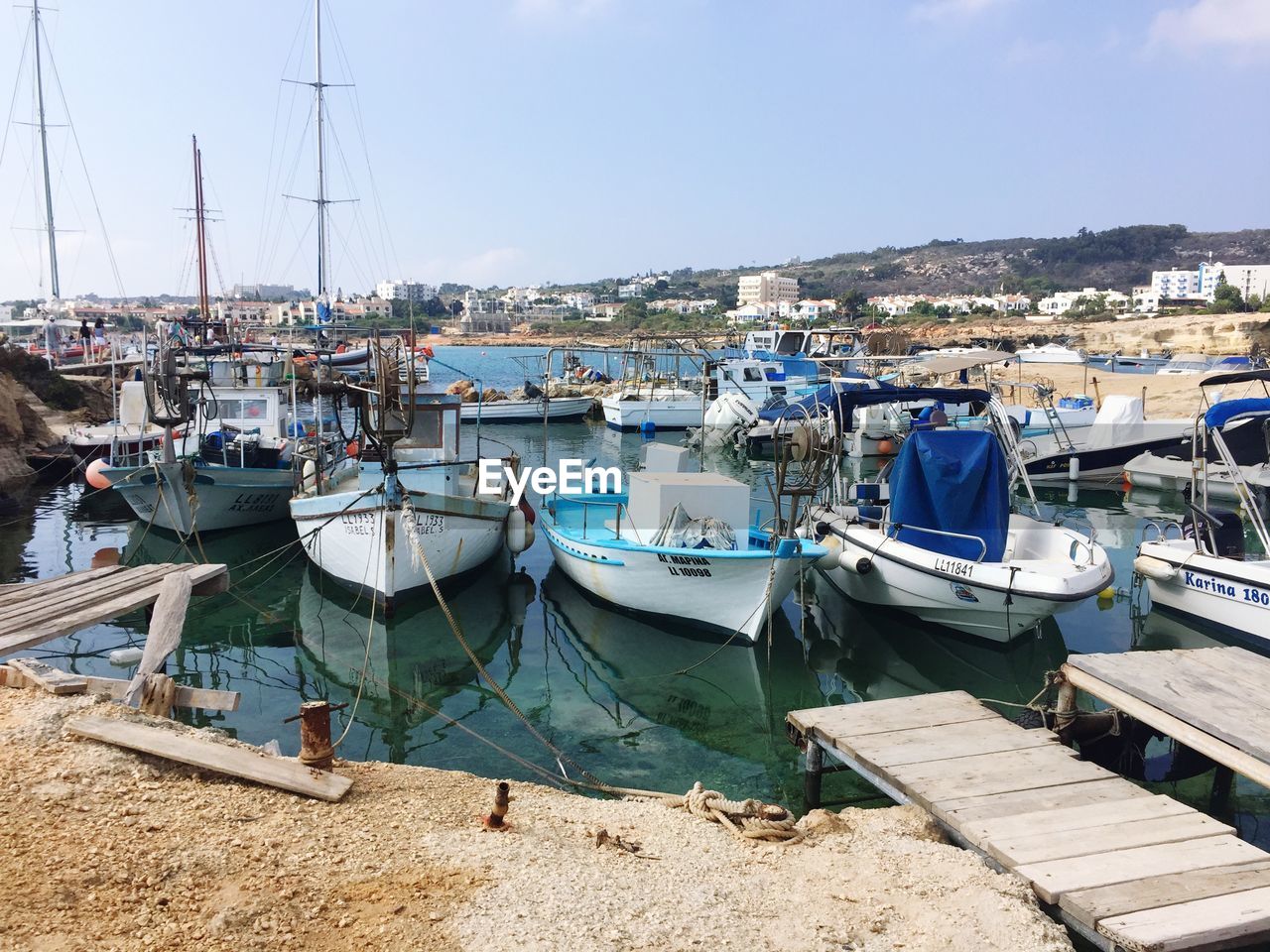 Boats moored at harbor against blue sky