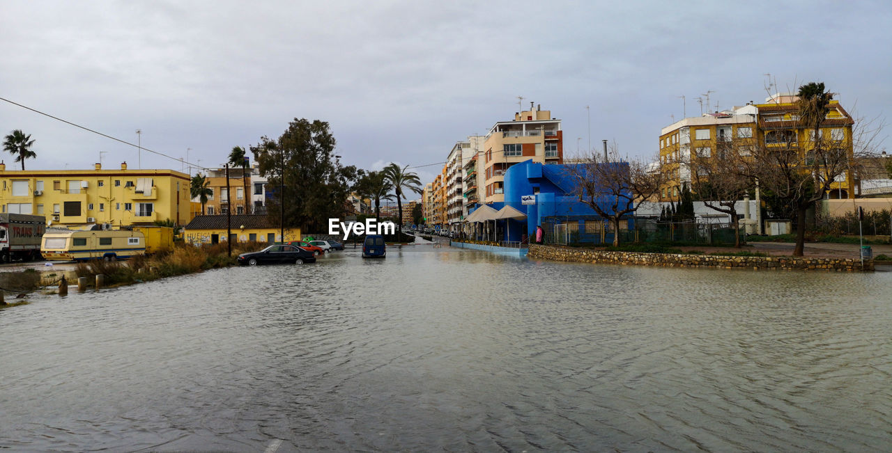 RIVER AMIDST BUILDINGS AGAINST SKY IN CITY